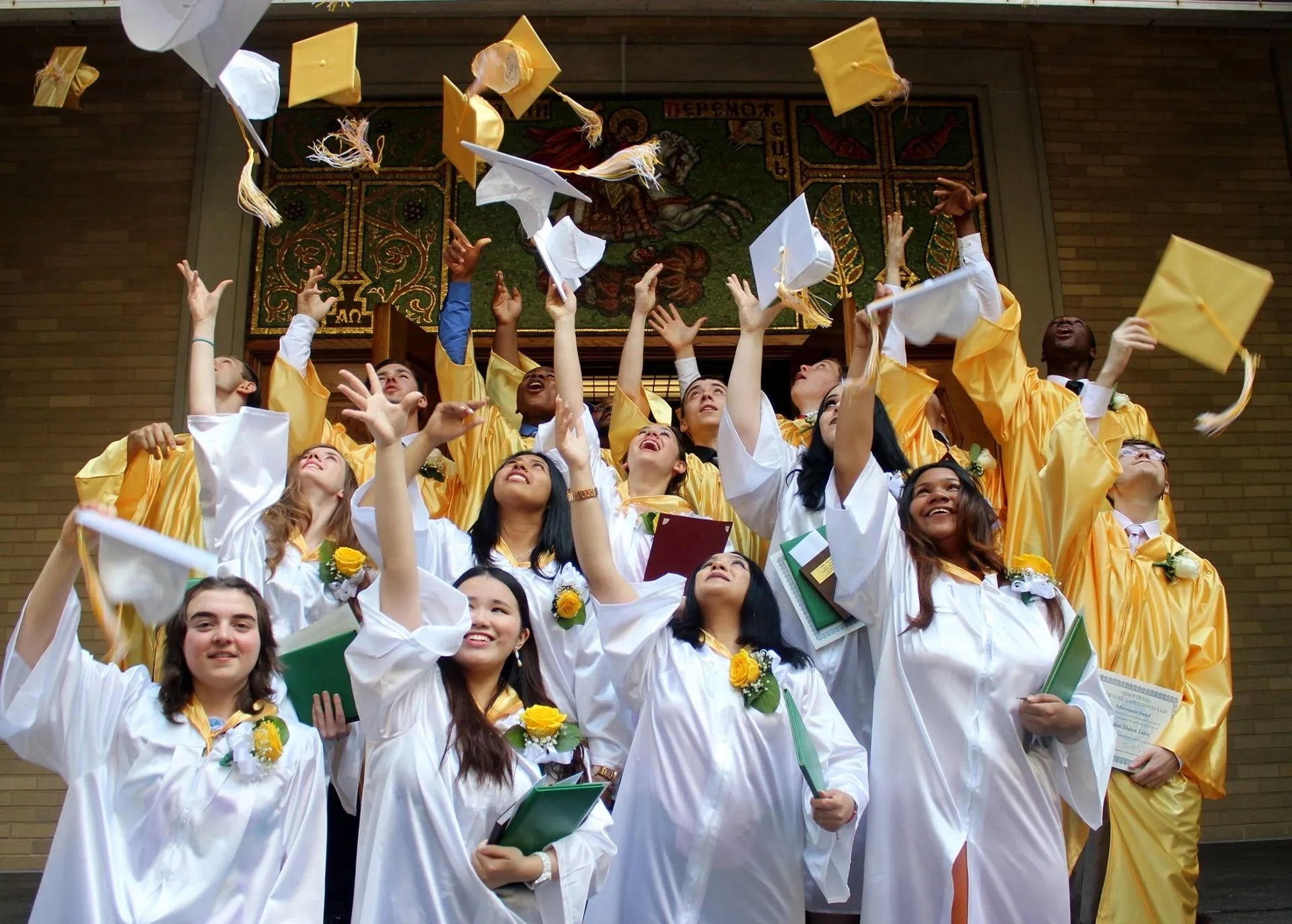 Graduates celebrating by tossing caps in air.