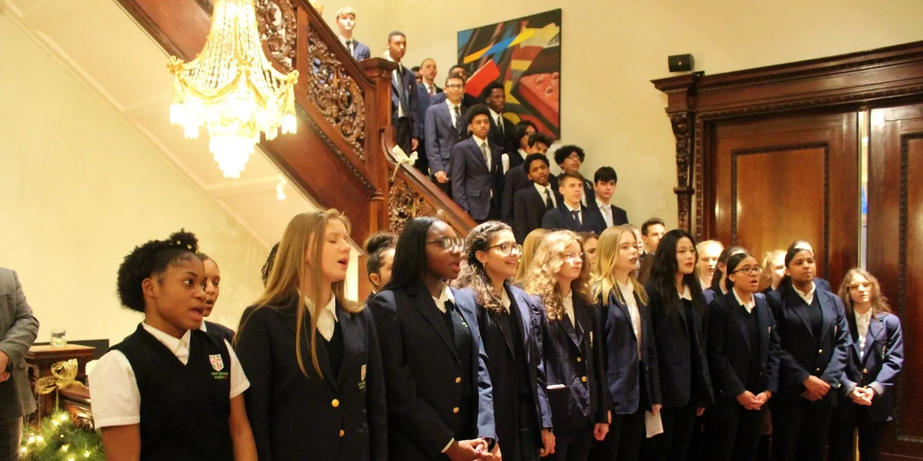 Students singing on staircase in formal attire.