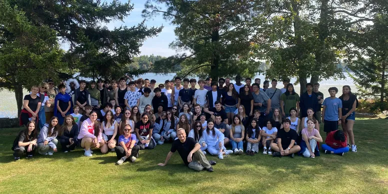 Large group of people outdoors, trees background.