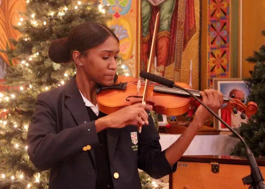 Young woman playing violin at festive event.